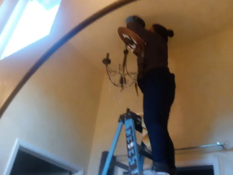 Electrician installing a chandelier in a Roscoe residence